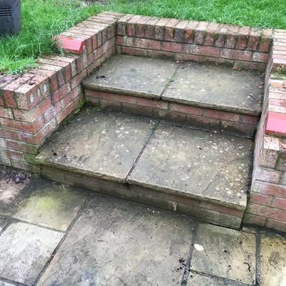 Stone-topped brick steps before cleaning, darkened treads