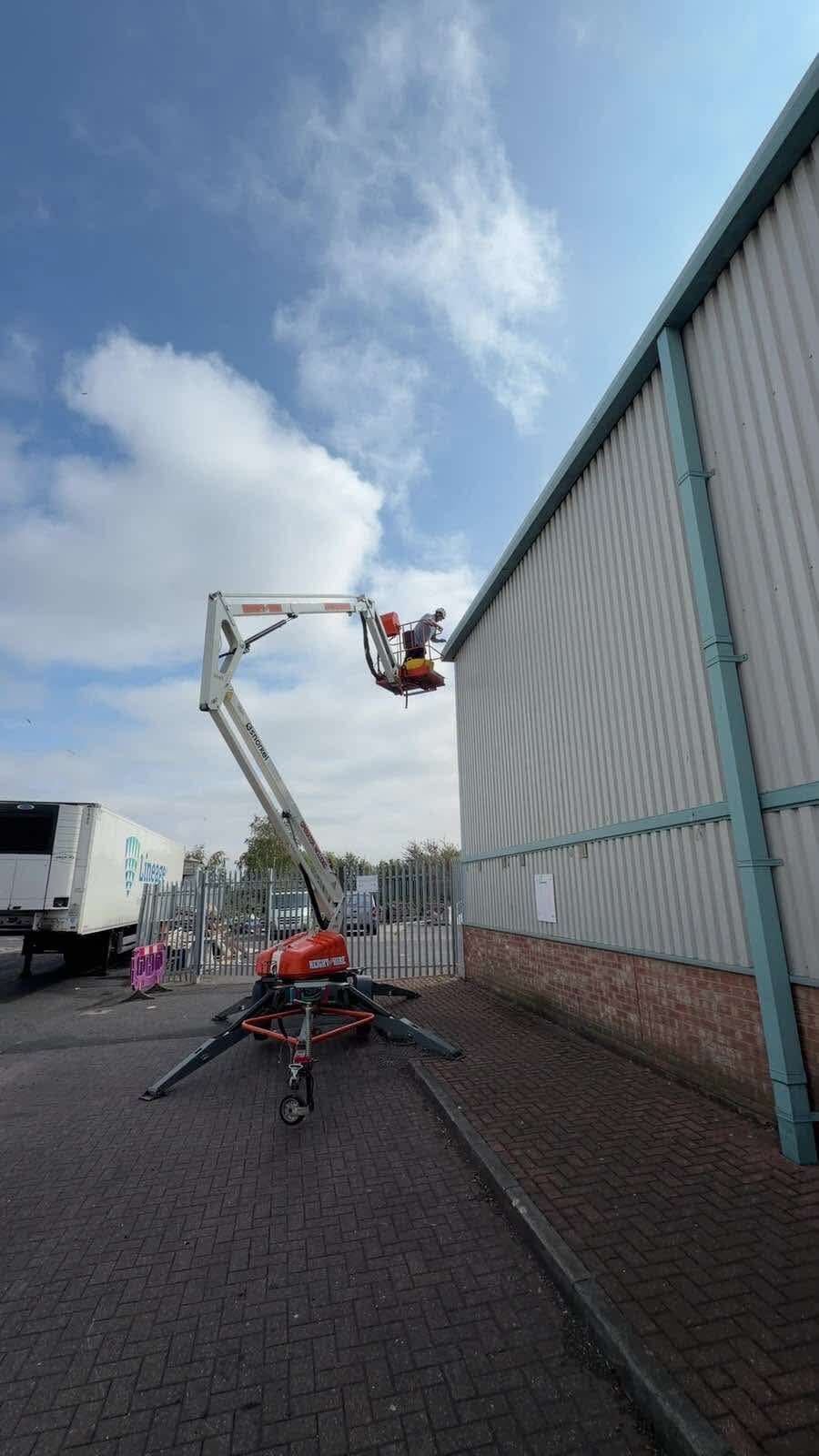 Cherry picker alongside the roofline of a commercial warehouse